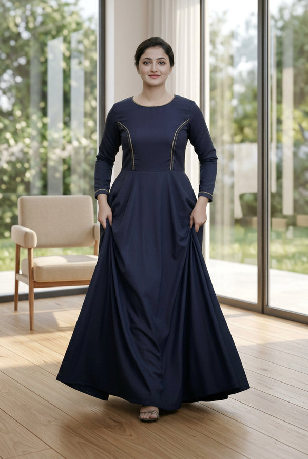 Woman in a long dark blue dress standing outdoors with greenery in the background